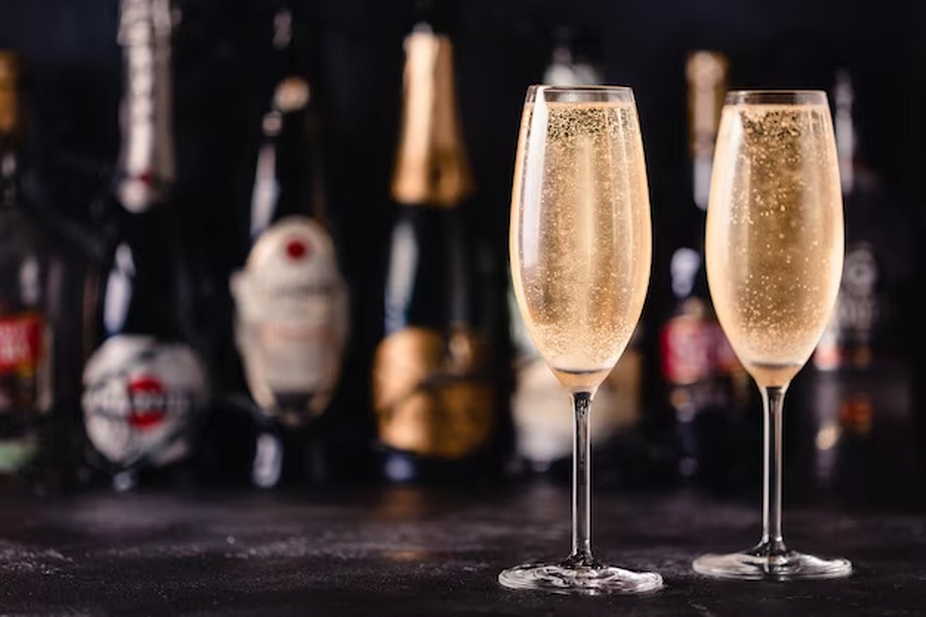 Two Wine Glasses with Sparkling Wine and Blurry Bottles in the Background